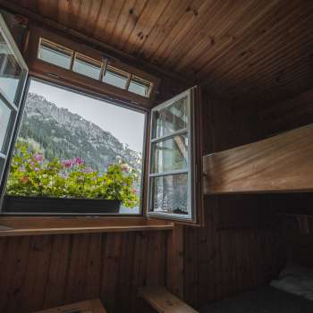 Window view from the dormitory: View of the mountain landscape from a simple dormitory with bunk beds at the Gafadura hut