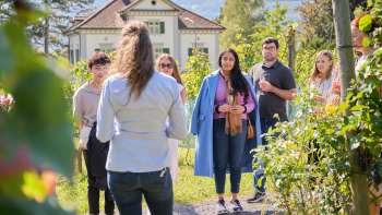 Guided tour of the Court Winery of the Prince of Liechtenstein, where a woman informs the group about wine and culture in the middle of the vines