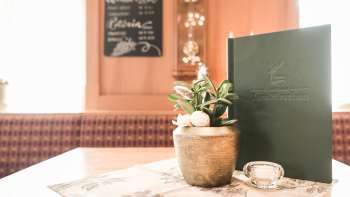Close-up of a table setting with menu cards, flowers and rustic decorations