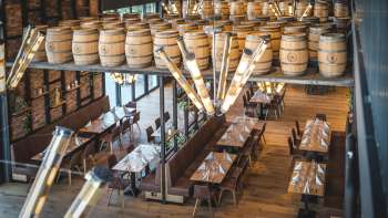 Inviting brewery room with long wooden tables, barrel decorations and stylish lighting