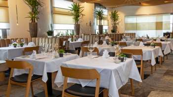 View of the stylishly furnished Alpspitz restaurant with white-clothed tables and a modern, bright atmosphere.
