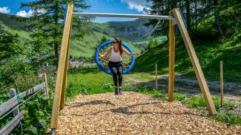 A woman swings in the Liechtenstein mountains and enjoys the view
