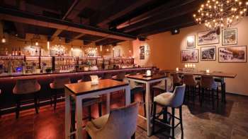 Elegant restaurant interior with dark wood elements, bar area and comfortable chairs in a cozy ambience.