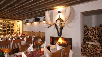 Cozy restaurant ambience with rustic wooden beams, white tablecloths and a crackling fireplace.