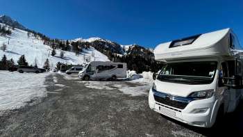 Several motorhomes are parked on the sunny pitch in Malbun with a mountain panorama in the background