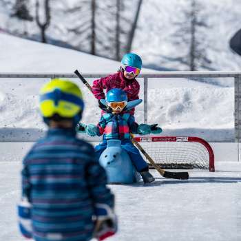 Family ice skating in Malbun, child sitting on an animal-shaped skating aid.