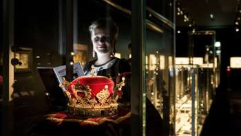 Young woman looking at a magnificent crown behind glass in the Liechtenstein NationalMuseum.
