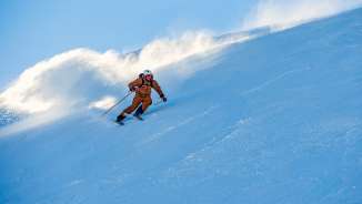 Marco Büchel skis down a snow-covered slope in Malbun, snow swirling up behind him.