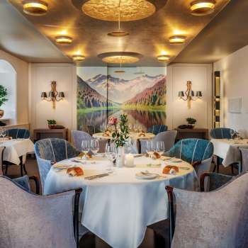 Round tables with wine glasses and candles in the elegant dining room of the Park Hotel Sonnenhof in Vaduz, Liechtenstein