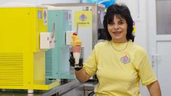A friendly ice cream vendor holds an ice cream in her hand in the Schaan ice cream bar