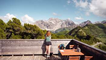 A woman enjoys the view of the Liechtenstein Alps and the Rhine Valley from the Sareis viewing terrace on a clear day