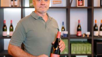 Harry Zech presents a bottle of his wine in the stylish sales room - regional wine culture from Liechtenstein.