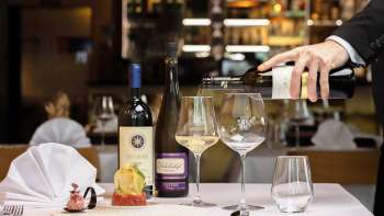 A waiter pours white wine to accompany an elegantly presented dish in the Alpspitz restaurant.
