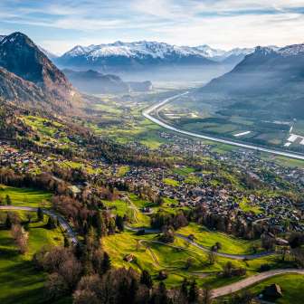 Sweeping views from the hillside over the Rhine Valley with fields, villages and snow-capped mountains - a natural idyll in Liechtenstein