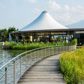 Steg at the Grossabünt bathing lake in Gamprin with a modern pavilion and a view of the mountains in the background
