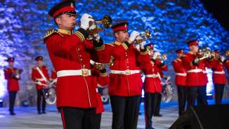 Brass band ensemble in eye-catching red uniforms at the Princely Tattoo 2022 in Liechtenstein - festive performance with traditional sounds.