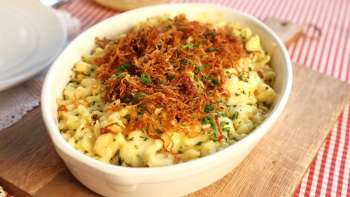 Traditional Käsknöpfle with fried onions - served in a plate on a wooden board