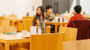Guests sit at wooden tables in the café in the Liechtenstein Art Museum, chatting and enjoying the atmosphere.
