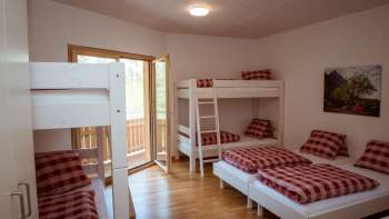 Family-friendly multi-bed room with bunk beds and single beds in the guest house at Camping Mittagsspitze.