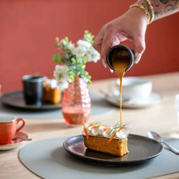 Dessert is topped with caramel sauce, coffee cups and stylish table decorations in the background