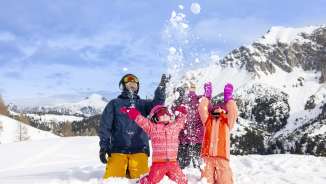 Family enjoying the snow together in Malbun - children happily throwing snowballs against a wintry mountain backdrop.