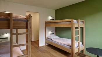 Four-bed room with bunk beds and wooden floor at Schaan/Vaduz Youth Hostel