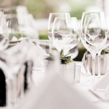 Close-up of several stacked wine glasses on a white table with luminous highlights.