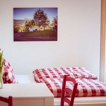 Cozy double room in the guest house at Camping Mittagsspitze with red and white checkered bed linen and decoration.