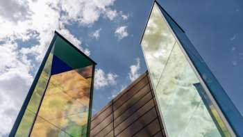 Art installation "Two Light Prisms" by Heinz Mack with colorful shimmering glass surfaces in front of a blue sky.