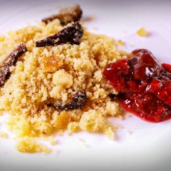 Traditional Riebel dish from Liechtenstein with crispy corn semolina and sweet roasted plums served on a white plate.