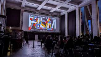 Visitors to the Schaan 2023 film festival sit in front of the screen in a modern evening setting in Liechtenstein