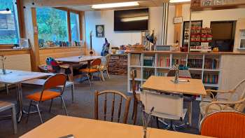View of the guest room with wooden wall and wall decoration - several tables with seating and a view of the decorative wall with guitars and green pictures.