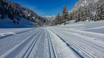 Freshly groomed cross-country ski trail in Steg with panoramic views of the snow-covered Alpine landscape