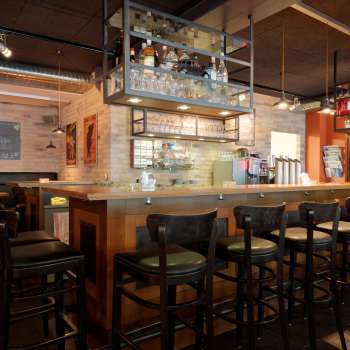 Stylish interior shot of the bar in the New Castle Vaduz with a well-stocked bottle rack and cozy seating area.