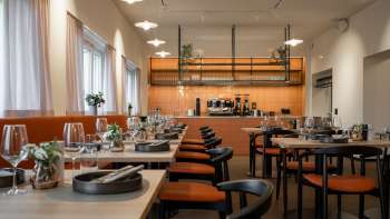 Modern restaurant with open kitchen area and elegantly laid tables Modern restaurant with open kitchen area and elegantly laid tables