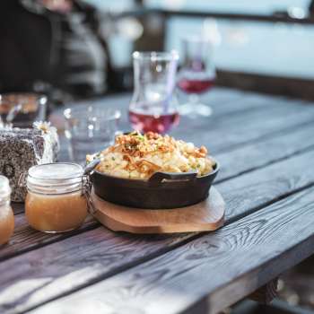 Regional specialty "Käsknöpflewith apple sauce on a wooden table in front of an alpine backdrop