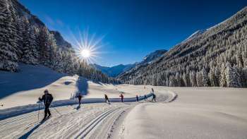 Cross-country skiers enjoy the freshly groomed trail in bright sunshine in Steg, Liechtenstein.