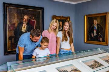 A family looks at exhibits in the Liechtenstein NationalMuseum in Vaduz, surrounded by historical paintings and portraits.