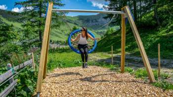 A woman swings in the Liechtenstein mountains and enjoys the view