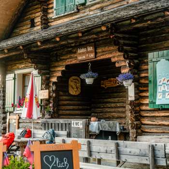 Entrance area of the hut: Rustic entrance area of the Gafadura hut with wooden facade, colorful flowers and information board