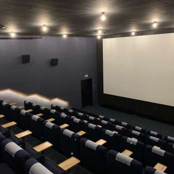 lick of the big screen at Skino Schaan, with rows of comfortable seats in a dark design.
